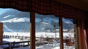 A view from a window overlooking a snowy landscape with mountains in the background, wooden fences, and a few buildings. - Alphotel Mittersill (Mittersill)