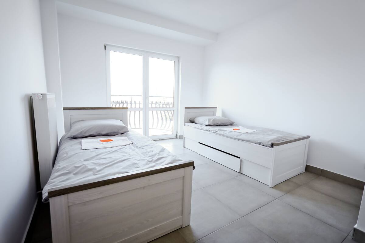 A bedroom with two single beds, a window, and a radiator.