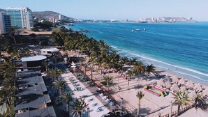 Ein Strandhotel mit Pool, Palmen und Blick auf den Ozean.