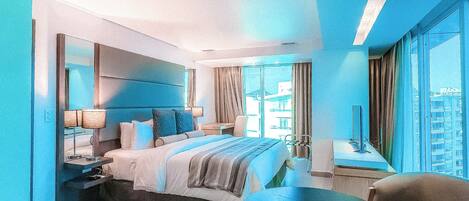 A modern hotel room with a curved bed, a round table, and a city view.