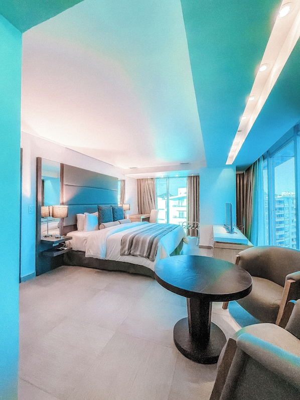 Une chambre d’hôtel moderne avec un lit aux courbes élégantes, une table ronde et une vue sur la ville.