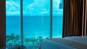 Ein Hotelzimmer mit einem großen Bett, einem Schreibtisch und Blick auf den Ozean.