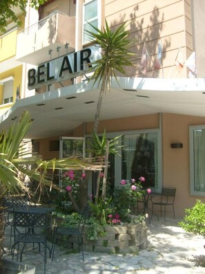 A hotel named 'BEL AIR' with outdoor seating and a palm tree. - Hotel Bel Air (Rimini)