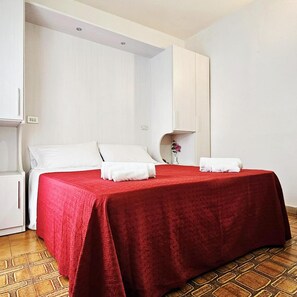 A hotel room with a bed, white walls, a red bedspread, and a white cabinet. - Hotel Bel Air (Rimini)