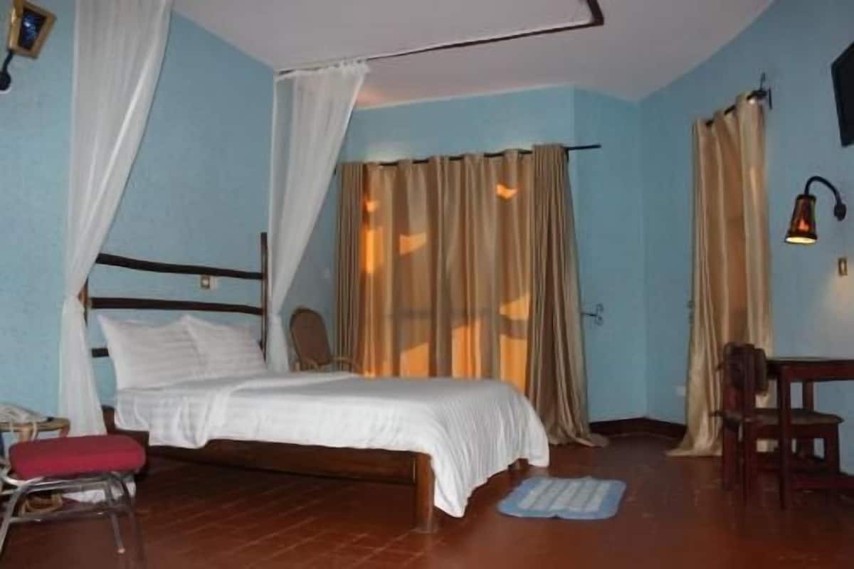 A room with a bed, a chair, a desk, and curtains.