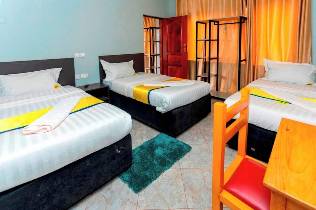 A hotel room with two beds, a small table, and a chair.