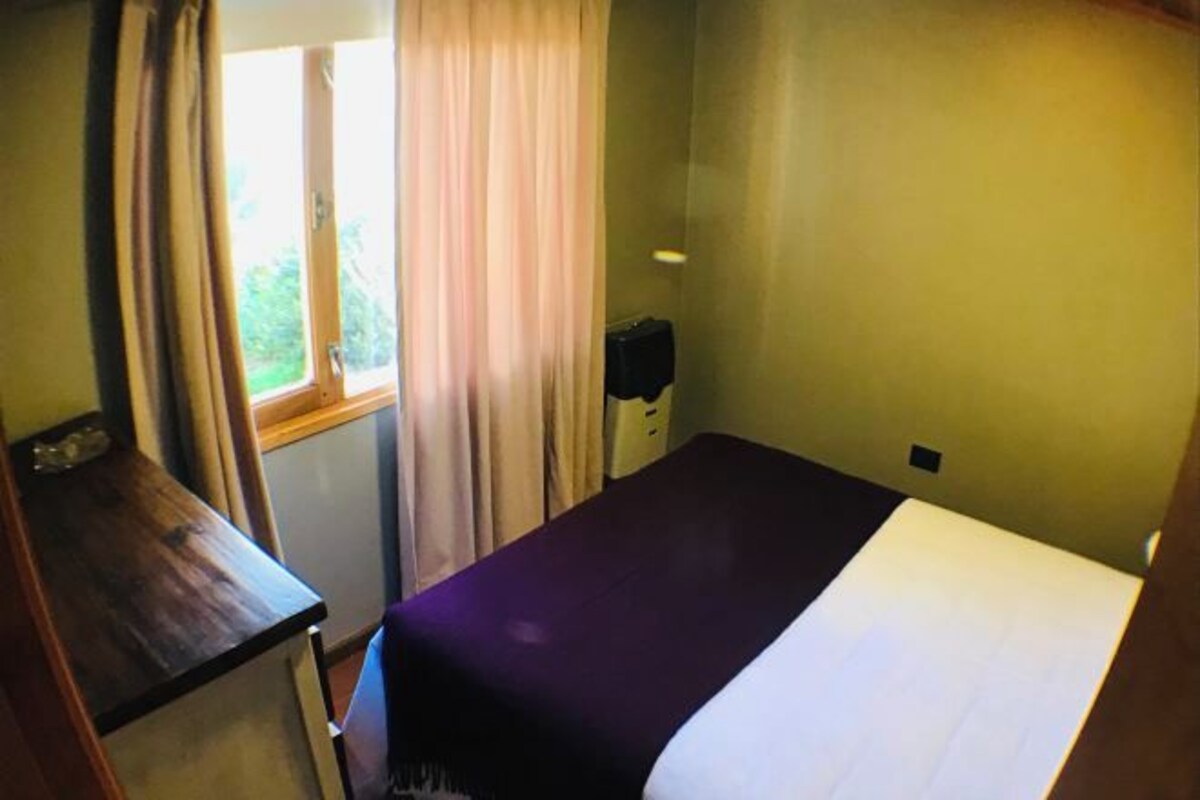 Une chambre avec un lit, un bureau et une fenêtre avec des rideaux.