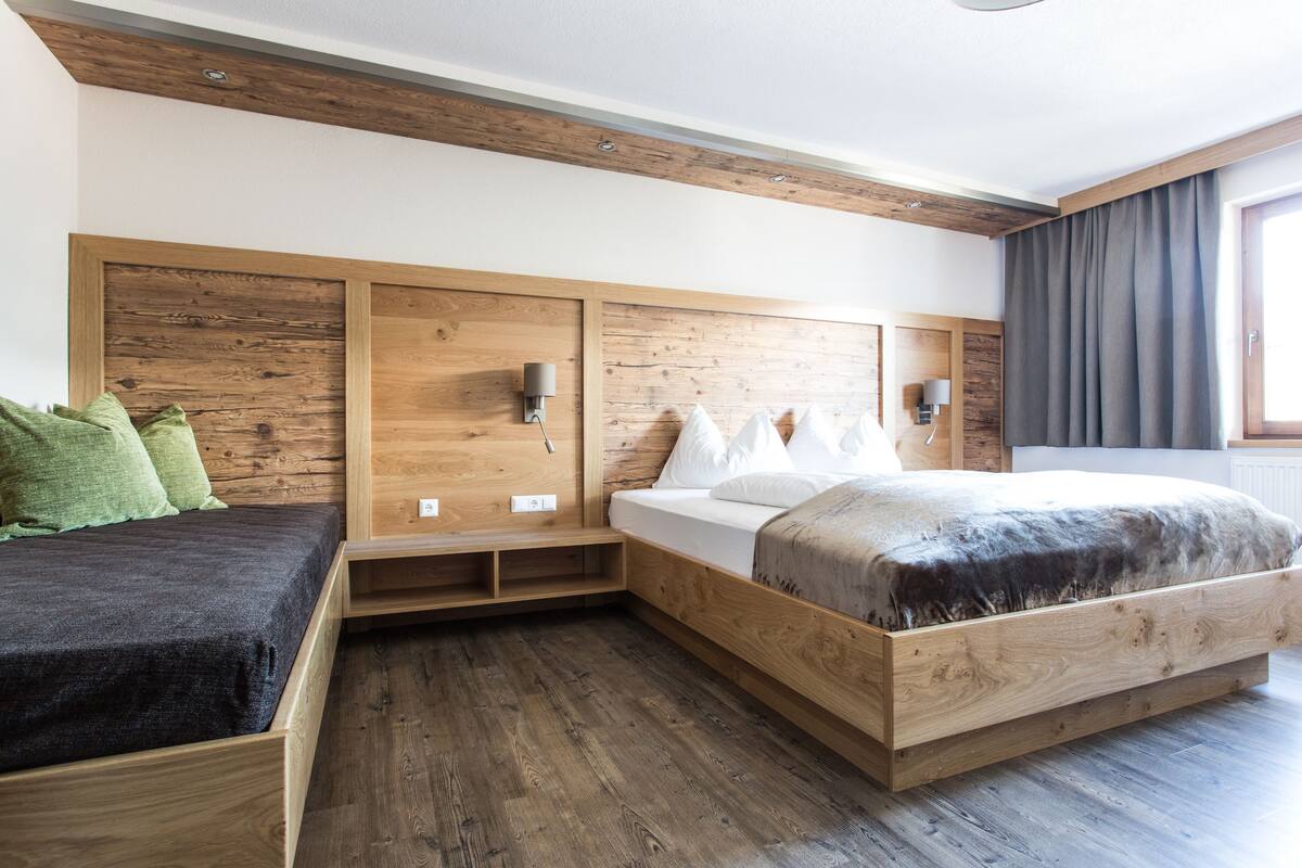 A modern bedroom with a wooden headboard, a bed with white linens, a bedside table, and a nightstand.