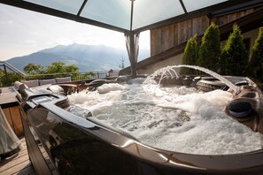 Un jacuzzi con terraza de madera y vistas a las montañas.