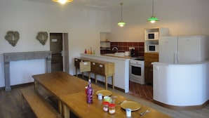 Una cocina compacta con una mesa de madera, un refrigerador, una estufa y un microondas.