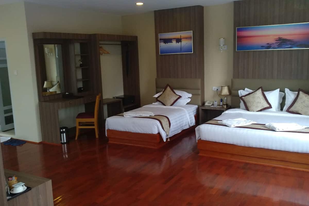 Une chambre d’hôtel avec deux lits, un bureau, une chaise, un miroir et un tableau au mur.