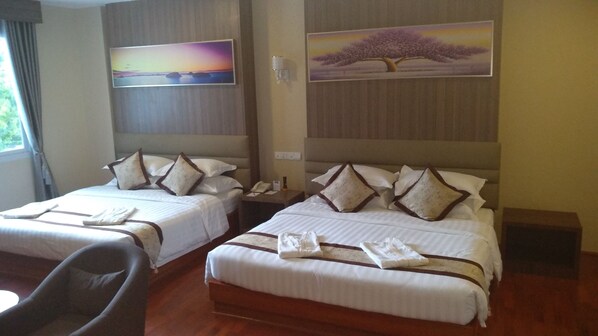 A hotel room with two beds, each with white linens and brown pillows, a wooden floor, and two paintings on the walls.