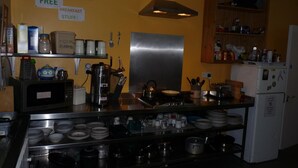Een keuken met roestvrijstalen apparatuur, een koffiezetapparaat en een bordje met daop aangegeven gratis ontbijt.