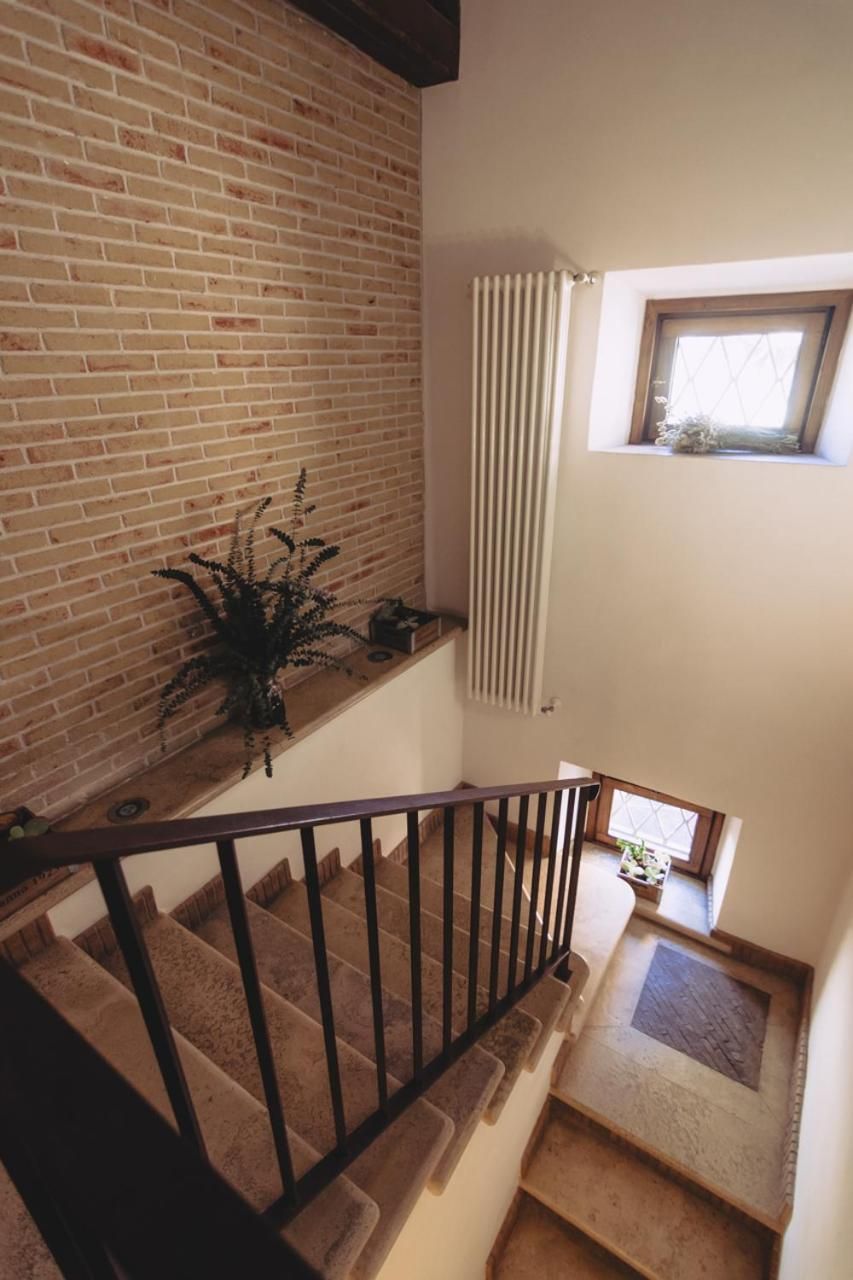 Una escalera junto a un muro de ladrillo, un radiador y una ventana con una planta.