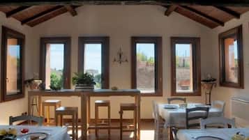 A dining area with wooden tables and chairs, large windows with views of the outdoors, and a rustic ceiling.