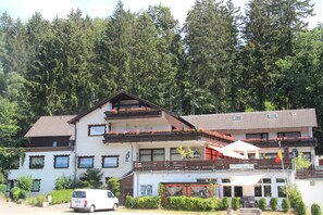 Un edificio de dos pisos con balcones, un restaurante y una bandera.