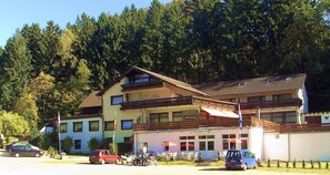 A multi-story building with a restaurant on the ground floor, surrounded by trees.