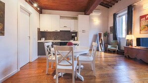Une cuisine moderne avec des meubles blancs, une table à manger avec des chaises et un plancher en bois.