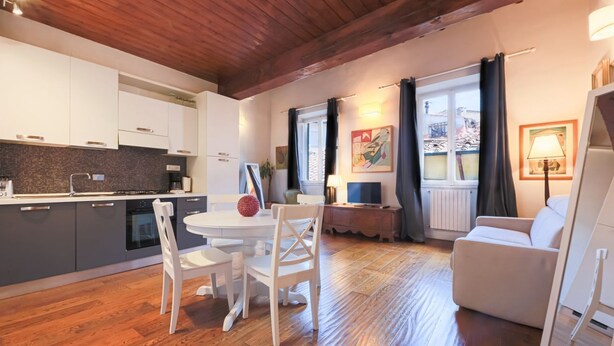 Une cuisine moderne avec des meubles blancs, une table à manger avec des chaises et un plancher en bois.