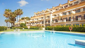 Ein Hotel mit Swimmingpool, Palmen und blauem Himmel.