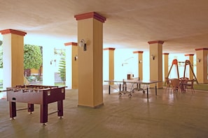A spacious indoor area with a foosball table, a table with chairs, and a swing set. - Romana Playa 902 (Marbella)