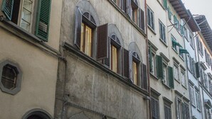 Une façade d’immeuble ornée de nombreuses fenêtres, dont certaines sont dotées de volets, et présentant un mélange de fenêtres en arc de cercle et de fenêtres rectangulaires.