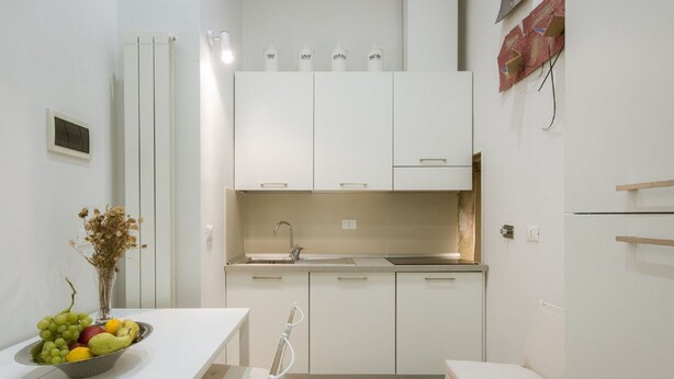 Une cuisine moderne avec des meubles blancs, un évier et un coin repas comprenant une table et des chaises.