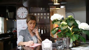 Una persona sentada en un escritorio con un reloj, llaves y un florero.