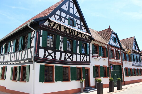 A traditional half-timbered building with green shutters and a sign indicating a restaurant. - Hotel zum Rössel (Kandel)