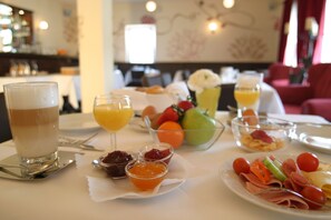 A breakfast table with various food items and drinks. - Hotel zum Rössel (Kandel)