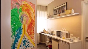 A compact kitchen with a microwave, kettle, and a small dining area. - Light Charme (Milan)