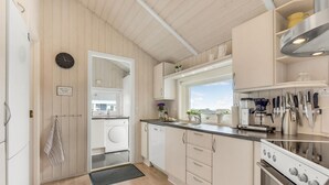 Una cocina moderna con lavadora integrada, cafetera y estufa.