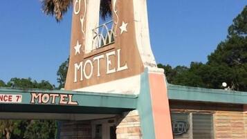 Señal de motel con la leyenda 'ARK MOTEL', un pequeño edificio y una palmera al fondo.