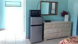 Une chambre équipée d’un réfrigérateur, d’un four à micro-ondes et d’un téléviseur fixé au mur.