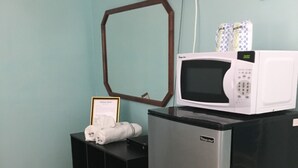 Une petite cuisine équipée d’un four à micro-ondes, d’un réfrigérateur et d’un petit placard contenant un certificat encadré.