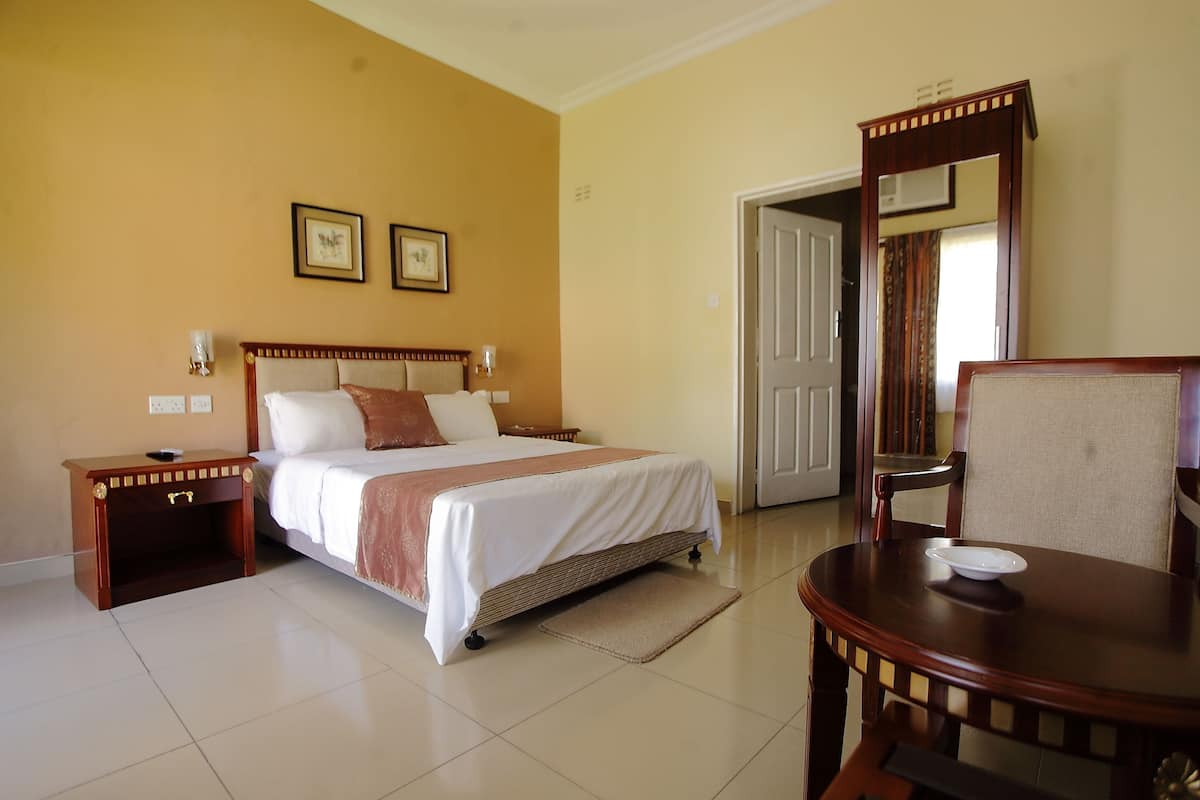 Quarto de hotel com uma cama, mesas de cabeceira, uma cadeira, uma mesa e um espelho.