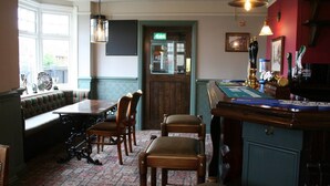 Un pub doté d’un bar, d’un espace salon et d’une moquette à motifs.