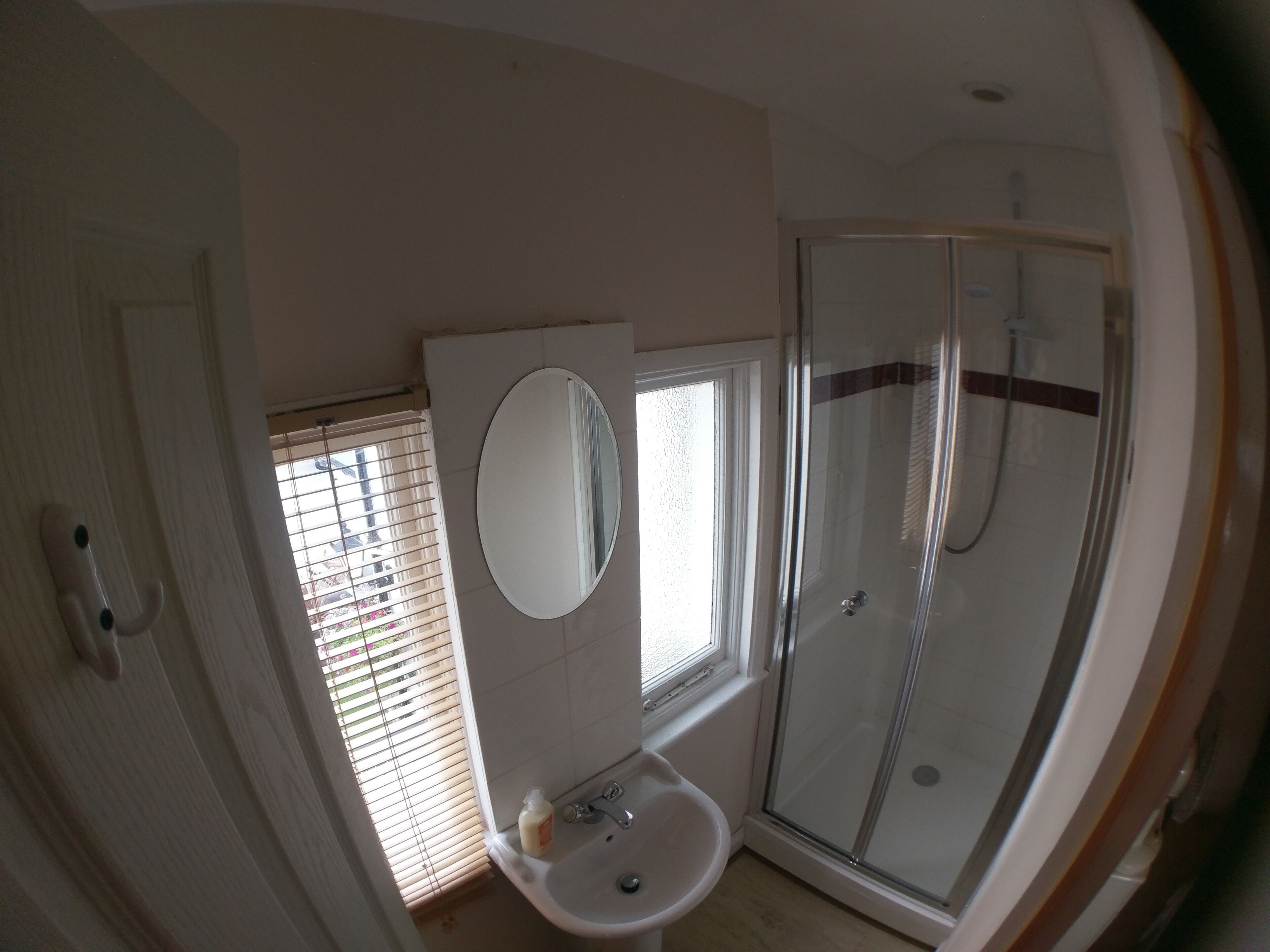 A bathroom with a glass shower enclosure, a sink, and a mirror.