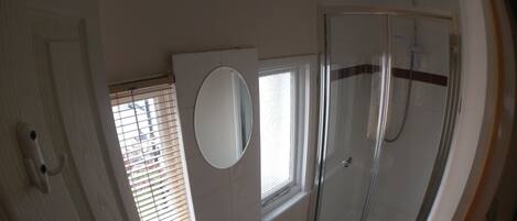 Un baño con cabina de ducha de vidrio, un lavamanos y un espejo.