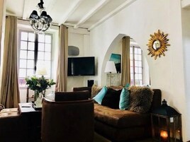 Una sala de estar con un sofá marrón, una mesa de centro, un televisor y una araña.