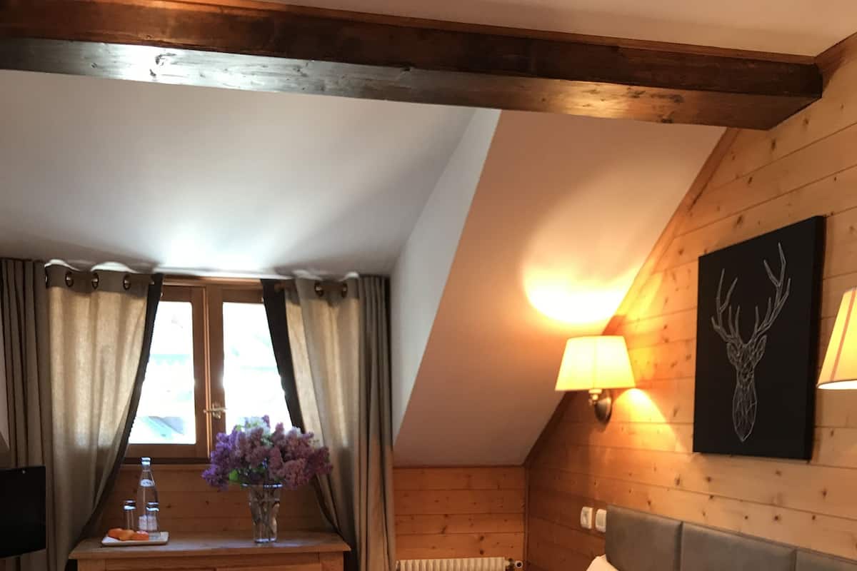 A bedroom with a bed, a dresser, a lamp, and a wall-mounted artwork.