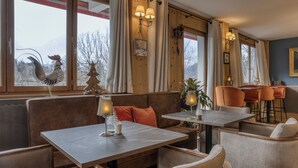 A cozy restaurant with wooden walls, a seating area with tables and chairs, and a view of the outdoors. - Hôtel Le Coeur des Neiges (Saint-Gervais-les-Bains)
