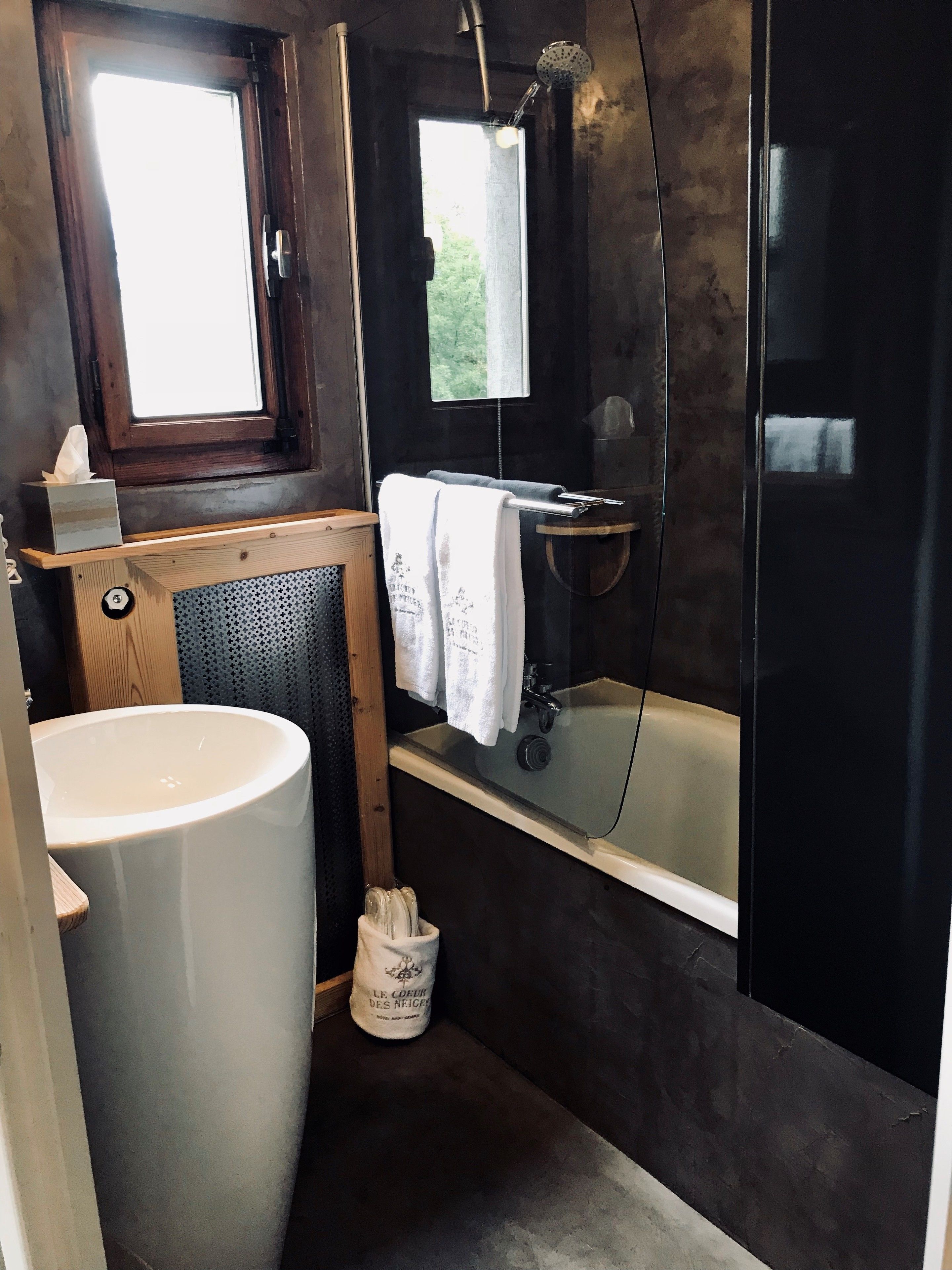 A modern bathroom with a large white sink, a bathtub, and a shower area.