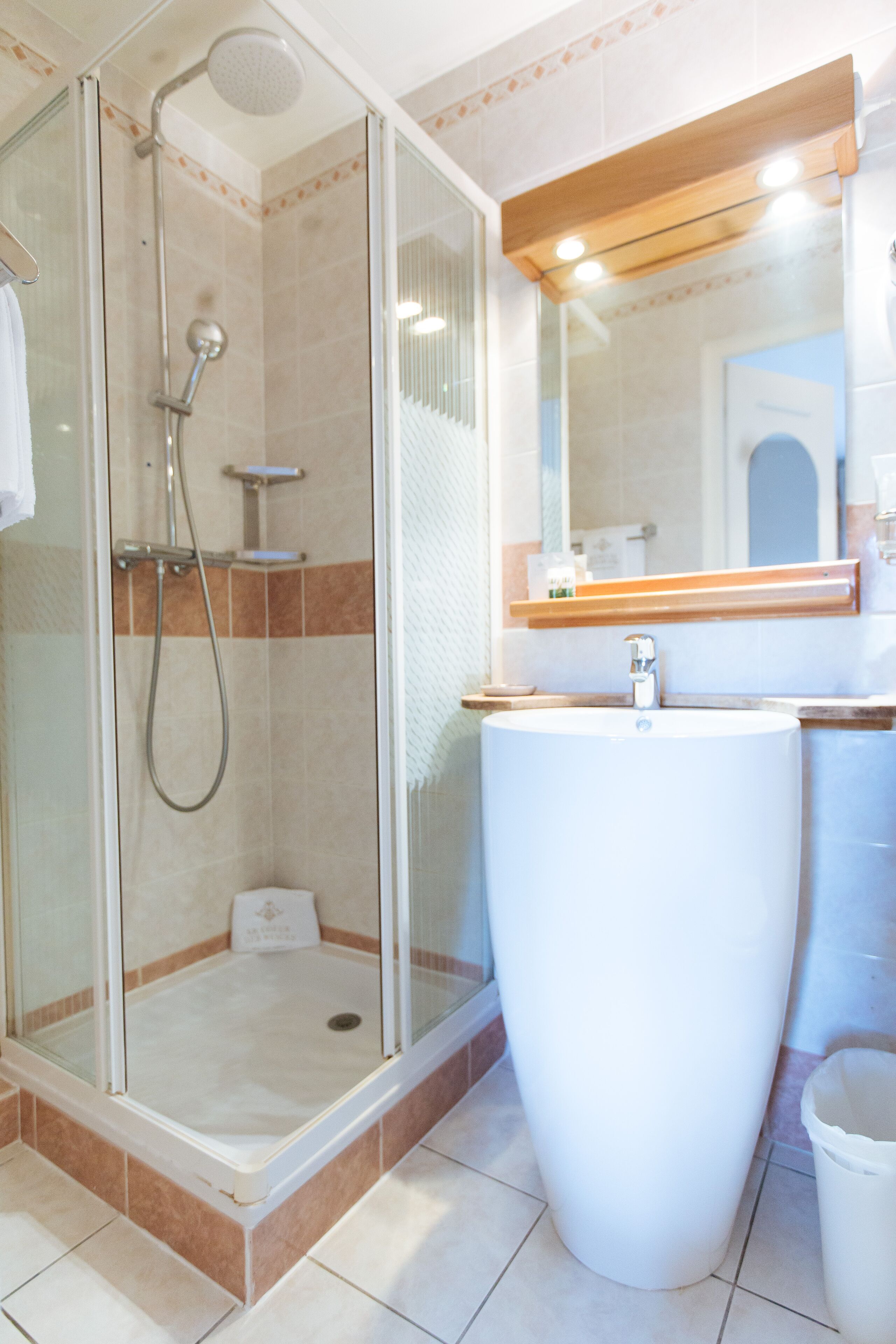 A bathroom with a glass-enclosed shower, a large sink, and a mirror above the sink.
