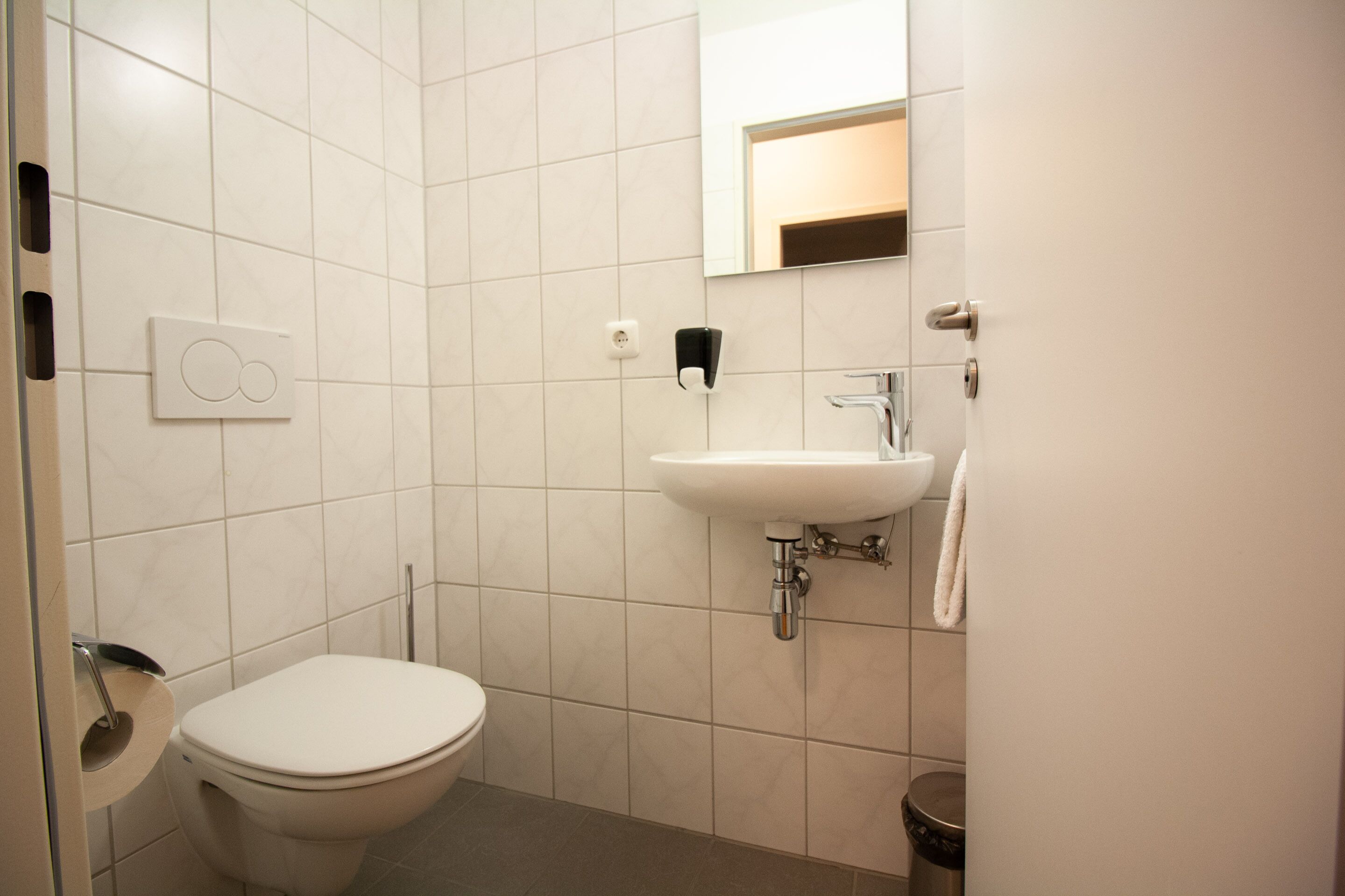 A small, modern bathroom with a toilet, sink, and mirror.