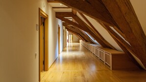 A long, narrow hallway with wooden beams and a wooden bench along one side.