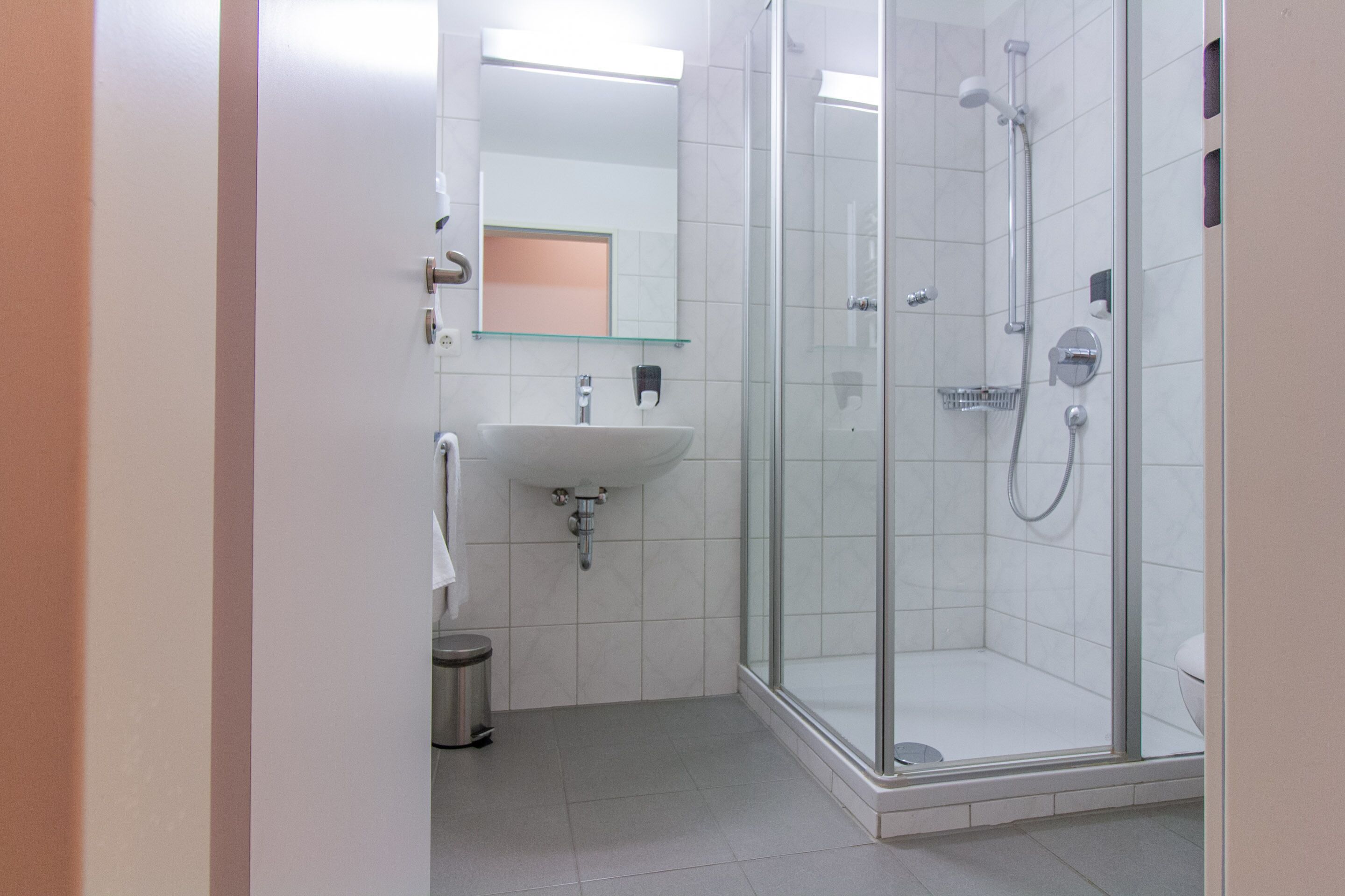 Une salle de bain moderne dotée d’une douche à parois de verre, d’un lavabo et d’un miroir.