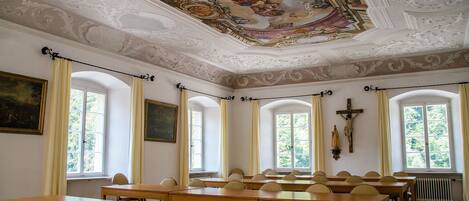 Una habitación con techo alto, frescos ornamentados y una cruz en la pared.