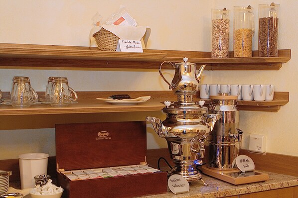 A coffee station with a coffee pot, sugar, creamer, and a sign indicating gluten-free options.