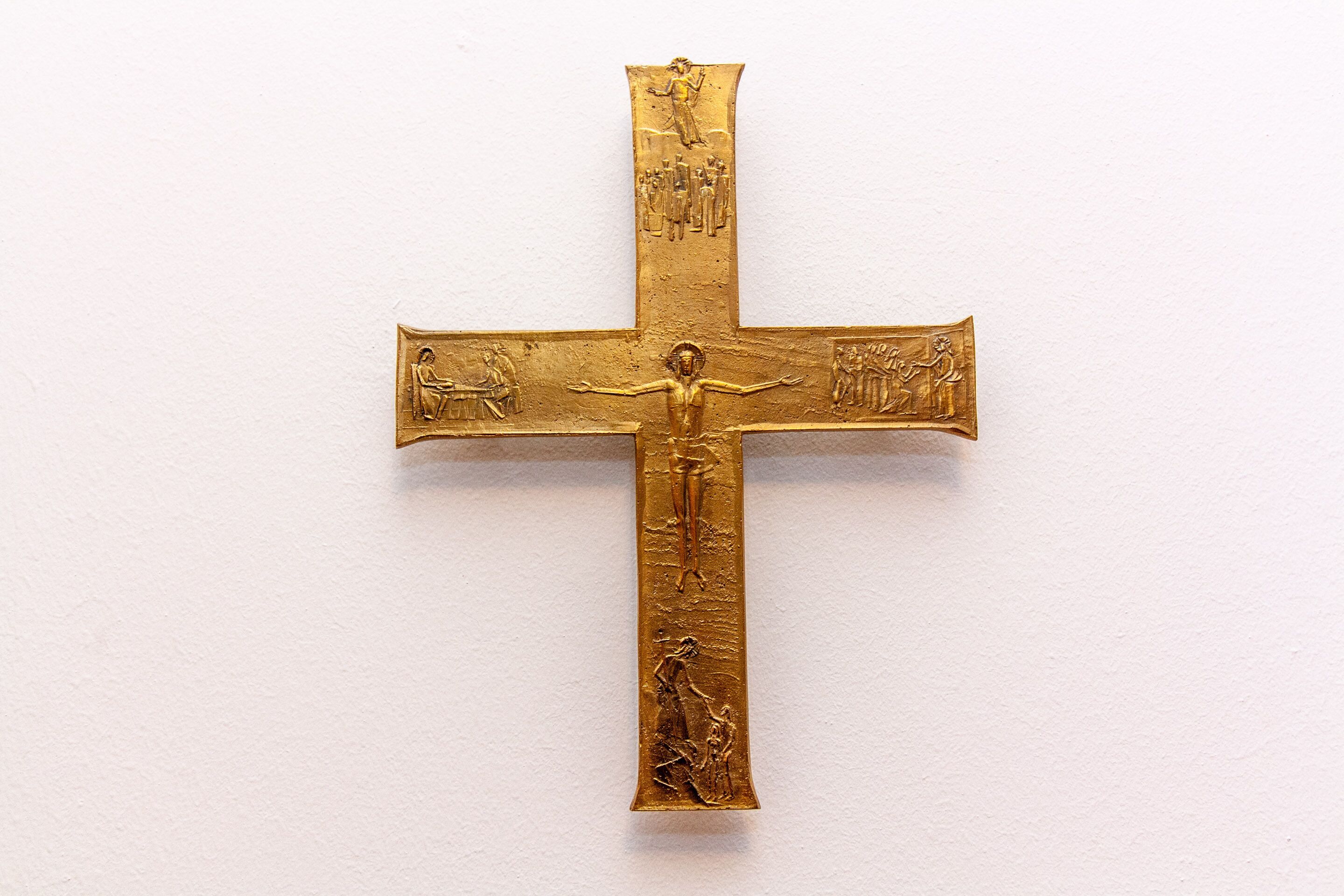 Une croix en or ornée de figures religieuses.